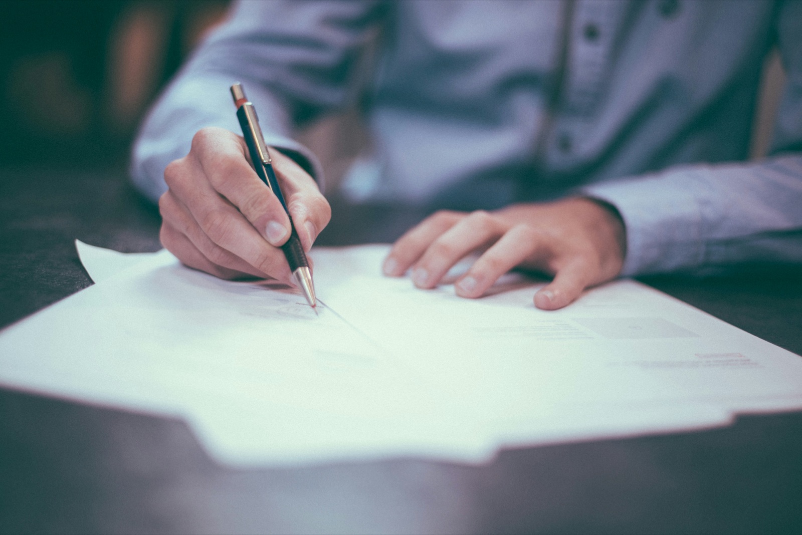A person signing a document with a pen