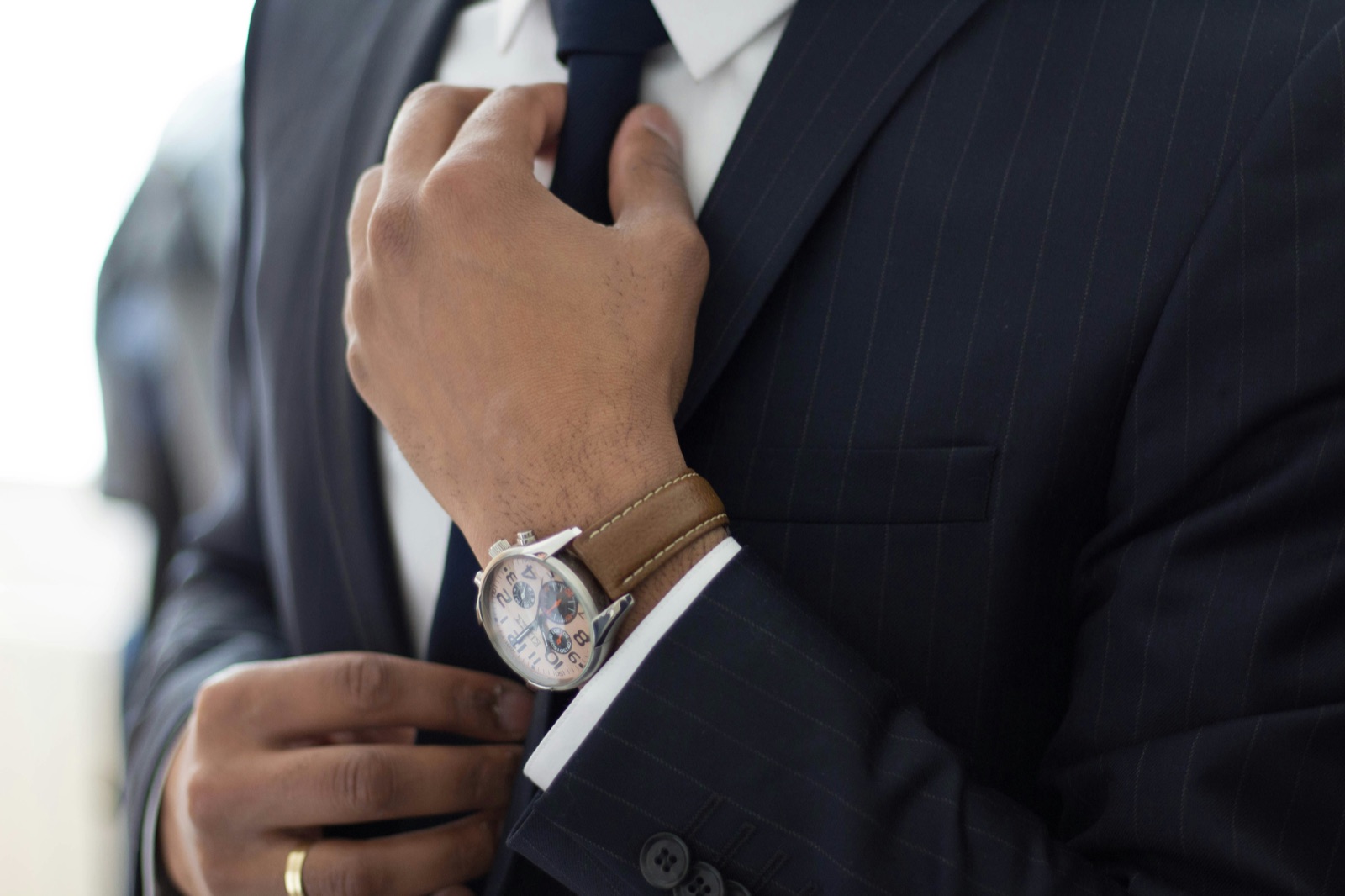 A professional in a suit checking a wristwatch